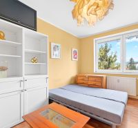 A bright room with a bed, shelves, and a floor with a wooden decor in a 3-room apartment.