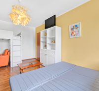 A sofa bed, a bunk bed, an orange armchair, and a wooden decor floor in a 3-room apartment.