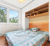 A bedroom in a 3-room apartment with a bed, storage space, and a floor with a wooden decor.