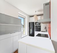 A bright kitchen with white furniture and black appliances in a 3-room apartment.