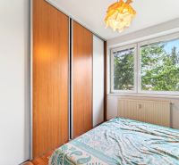 A bedroom with a large wardrobe, a bed, and a window in a 3-room apartment.
