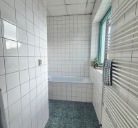 A bathroom with white tiles and a bathtub in the offices.