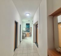 A hallway in offices with a tiled floor and doors to various rooms.