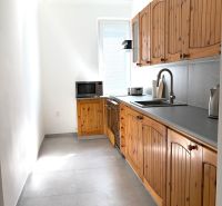 A kitchen in a 3-room apartment with wooden cabinets and ceramic tiles.