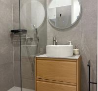 Bathroom with a shower, mirror, sink, and cabinet in a 3-room apartment.