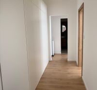 Interior of a 3-room apartment with white cabinets and a floor with a wood decor.