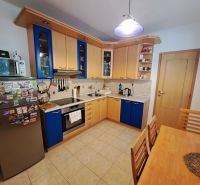 A kitchen in a 3-room apartment with a tiled floor and a wooden kitchen unit.