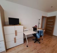 A room in a 3-room apartment with a wooden decor floor, a desk, and a wardrobe.