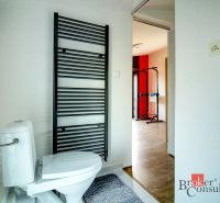 Bathroom with a toilet, radiator, and a view into the gym in a family house.