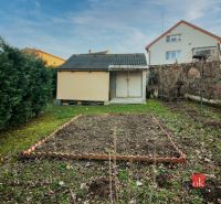 A garden at a family house in Suchá nad Parnou with a lawn and a small storage.