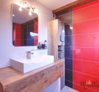 A bathroom in a family house with a sink, a mirror, and striking tiles.