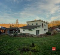 A family house in Suchá nad Parnou with a grassy garden and a gazebo at sunset.