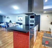 Open kitchen and living room with wood-patterned flooring in a family house.
