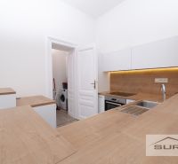A kitchen in a 2-room apartment with a wood-patterned floor and built-in appliances.