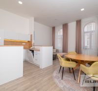 Interior of a 2-room apartment with a kitchen, dining table, and wooden decor flooring.