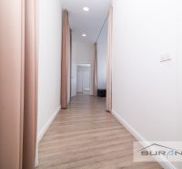 A hallway with a wooden decor floor, white walls, and light pink curtains in a 2-room apartment.