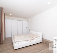 A bedroom with a white bed and a wooden decor floor in a 2-room apartment.