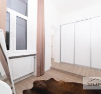 A bedroom with wood-patterned flooring, a mirror, and a large wardrobe.
