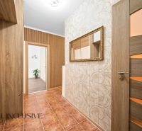 A hallway in a 2-room apartment with ceramic tiles, wooden doors, and a mirror on the wall.