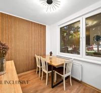 Dining area with a table, chairs, wooden wall, and floor with a wooden decor in a 2-room apartment.