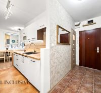 A kitchen in a 2-room apartment with white cabinets and tiled flooring.