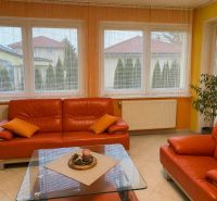 Living room with an orange sofa and large windows in a family house.