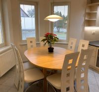 Dining area in a family house with a table, chairs, and a flower on the table.