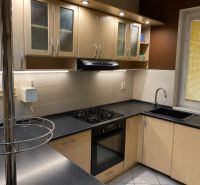 A kitchen in a family house with a corner kitchen unit and a black sink.