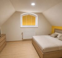 A bedroom in a family house with a wooden decor floor, a double bed, and a dresser.
