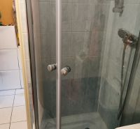 Bathroom in a studio apartment with a shower cabin and white tiles.