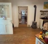 Interior of a family house with a fireplace, wooden decor flooring, and open doors.