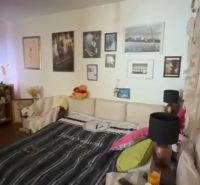 Bedroom in a family house with a couch, photos on the wall, and a bed with decorative pillows.