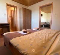 A bedroom in a family house with a bed, a table, a chair, and towels on the blanket.