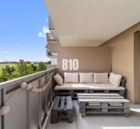 A balcony in a 4-room apartment with a view of the surroundings of Nitra and wooden seating made from pallets.