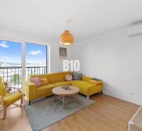 Living room of a 4-room apartment with a yellow sofa and a large window, floor with wooden decor.
