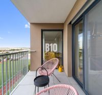 The balcony of a 4-room apartment in Nitra with a view of the sports field and comfortable seating.