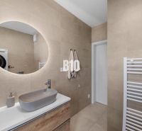 A bathroom in a 4-room apartment with a round mirror and a sink on beige walls.