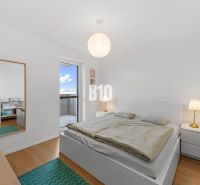 A bright bedroom with wood-patterned flooring and access to a balcony in a 4-room apartment.