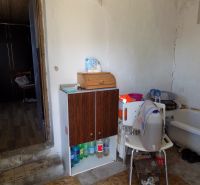 A kitchen in a cottage with a storage cabinet and a bathtub, floor with wood decor.