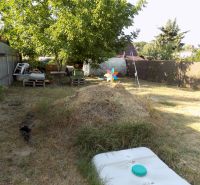 The garden by the Cottage on the Pumpkin Field in Nové Zámky with a pile of hay and a tree.