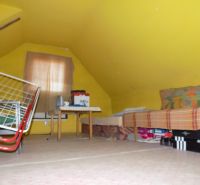 Yellow attic in a cottage with a bed and a folding chair.