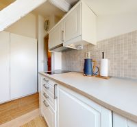 A kitchen in a studio apartment with light cabinets and a cooktop.