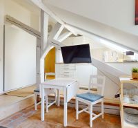 Attic space with a television and a dining table in a studio apartment.