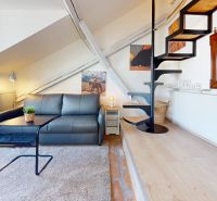 Attic living room in a studio apartment with wood-patterned flooring and spiral staircase.