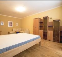 Bedroom in a 3-room apartment with a bed, wardrobe, and wooden decor flooring.