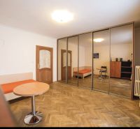 A room in a 3-room apartment with a wooden decor floor and a large mirrored wardrobe.