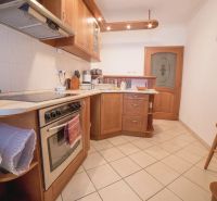 A kitchen in a 3-room apartment with wooden cabinets and ceramic flooring.