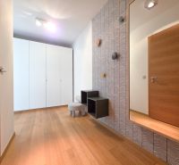 Interior of a 1-room apartment with a wood-patterned floor, a white wardrobe, and a mirror.