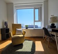 Stylish armchair, writing desk, and wooden decor flooring in a studio apartment.