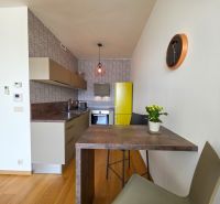 A kitchen in a studio apartment with a yellow refrigerator and wallpapered walls.